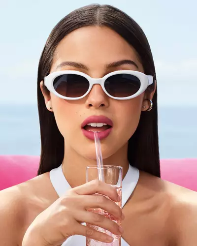 Beyaz guneş gozluğu takan ve mauve dudak gorunumuyle Olivia Rodrigo.