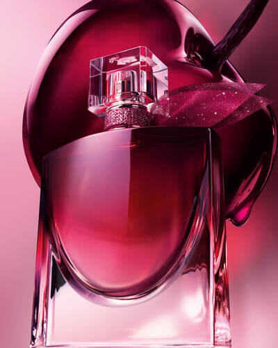 Bordo parfum şişesinin, buyuk ve parlak koyu bir kirazın onunde konumlandığı yakın plan sanatsal bir cekim.