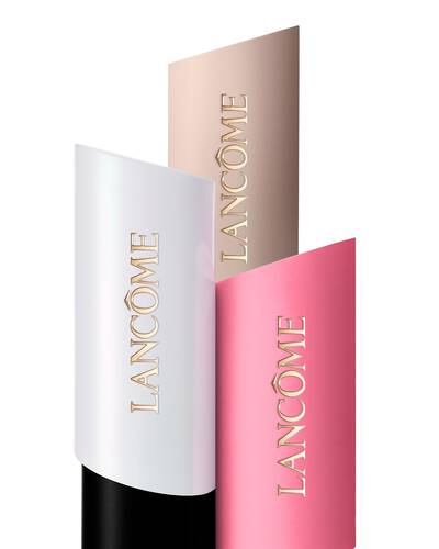 Beyaz, bej ve pembe renklerde uc Lancome Teint Idole Shape Stick Foundation, Highlighter ve Blush’ın katmanlı duzeni.