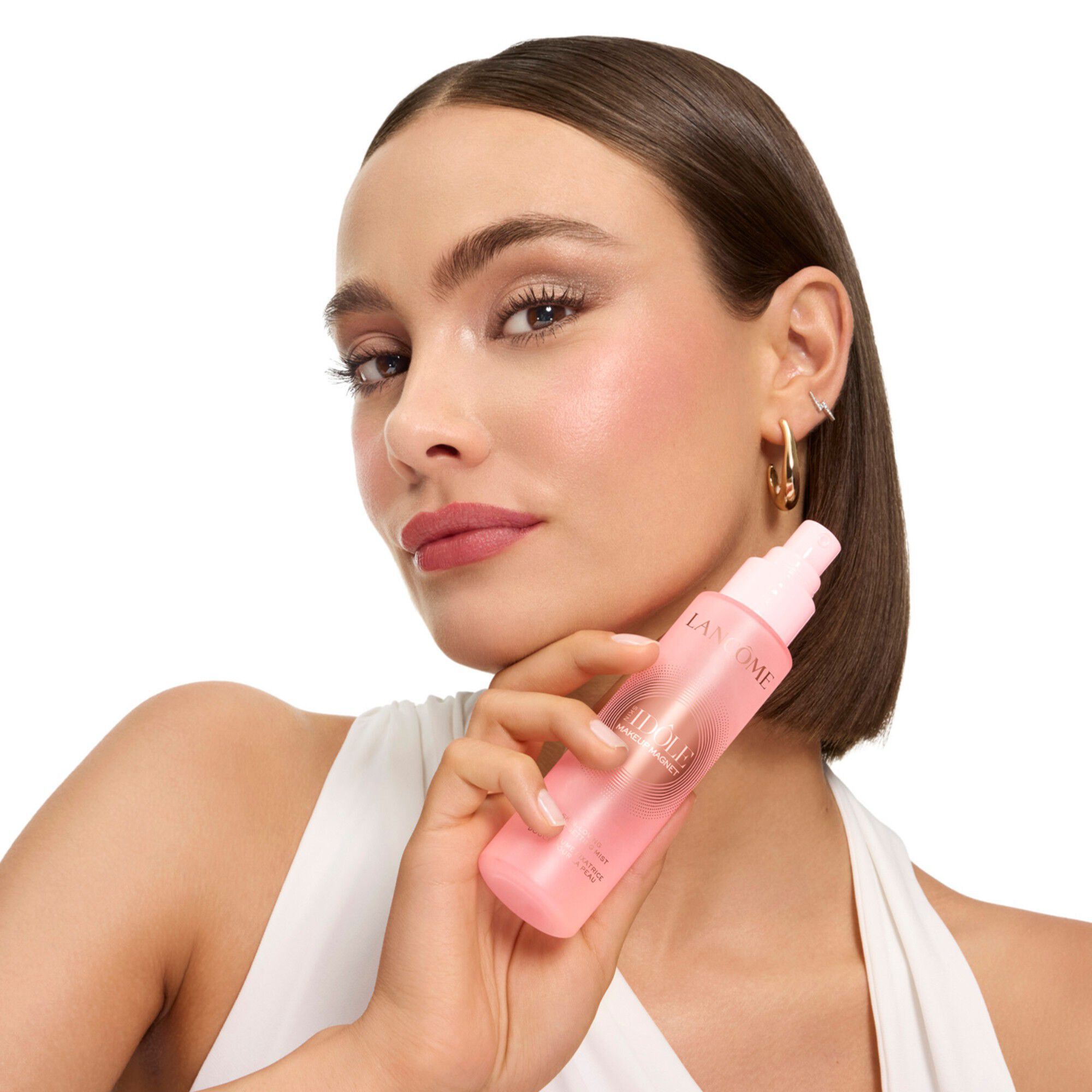 Pembe Idole sabitleyici mist’i yuzunun yanında tutan model.