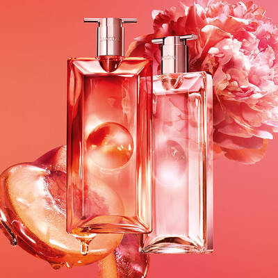 Two Lancome perfume bottles with peaches and a pink flower.